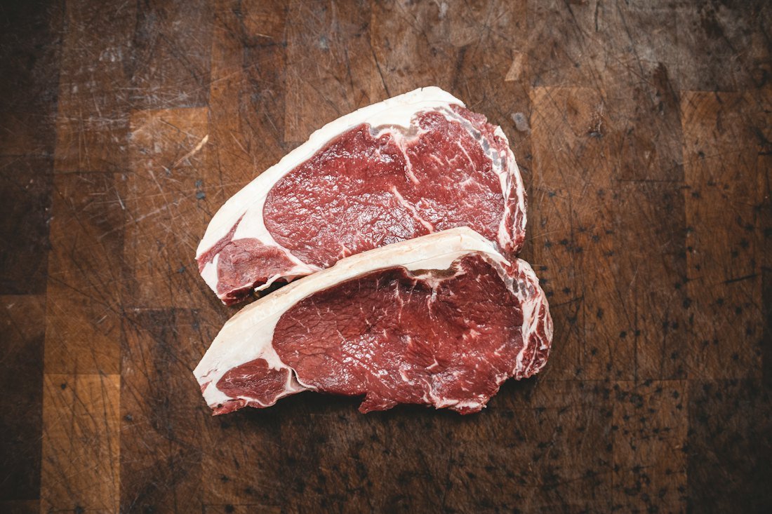 Two raw ribeye steaks with rich marbling